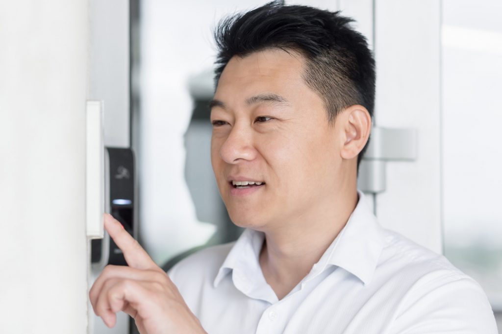Close-up photo.Portrait of a young Asian man, calling the intercom of the house, pressing the button